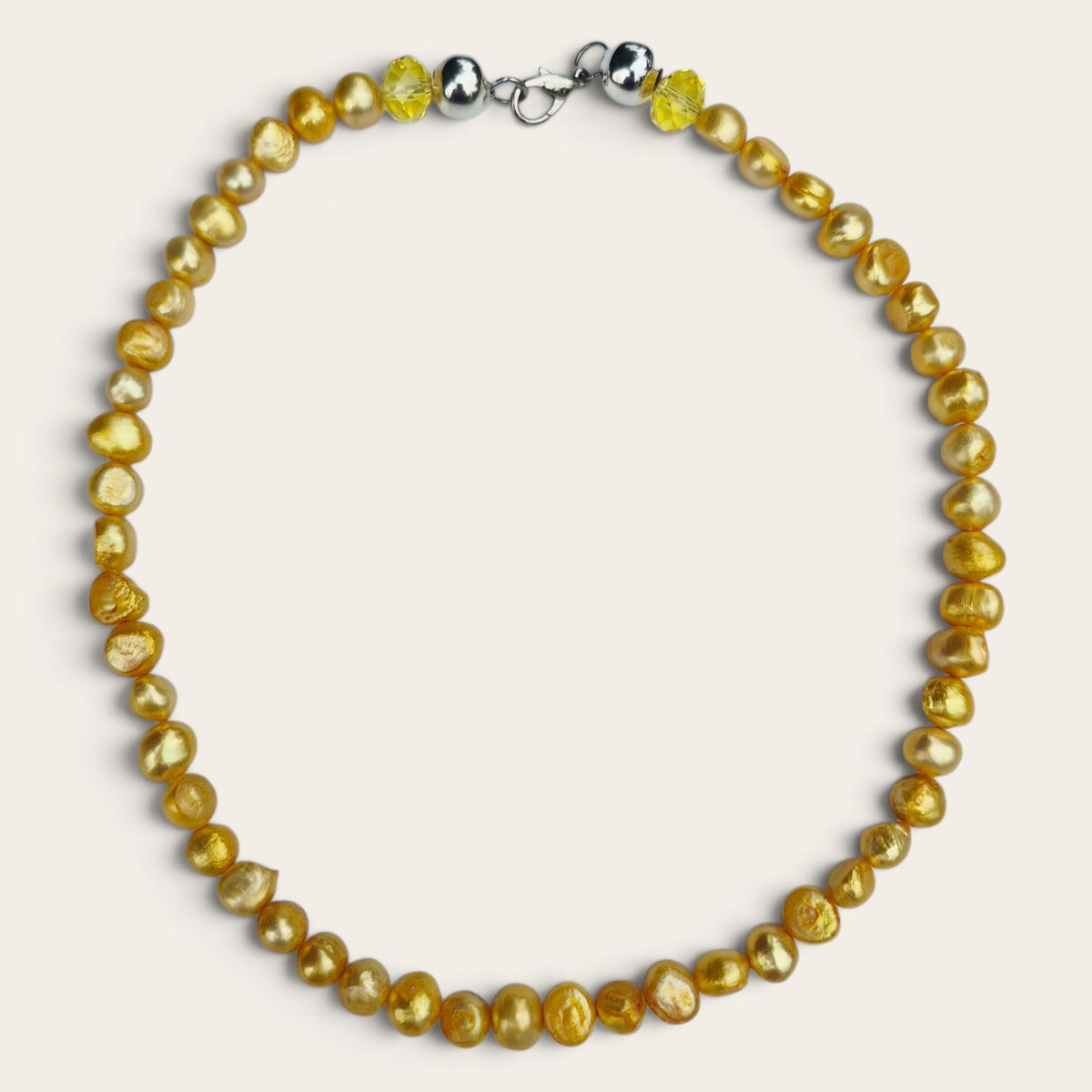 Collar semicorto de perlas de río amarillas teñidas, con formas irregulares y cierre metálico plateado, sobre fondo claro.